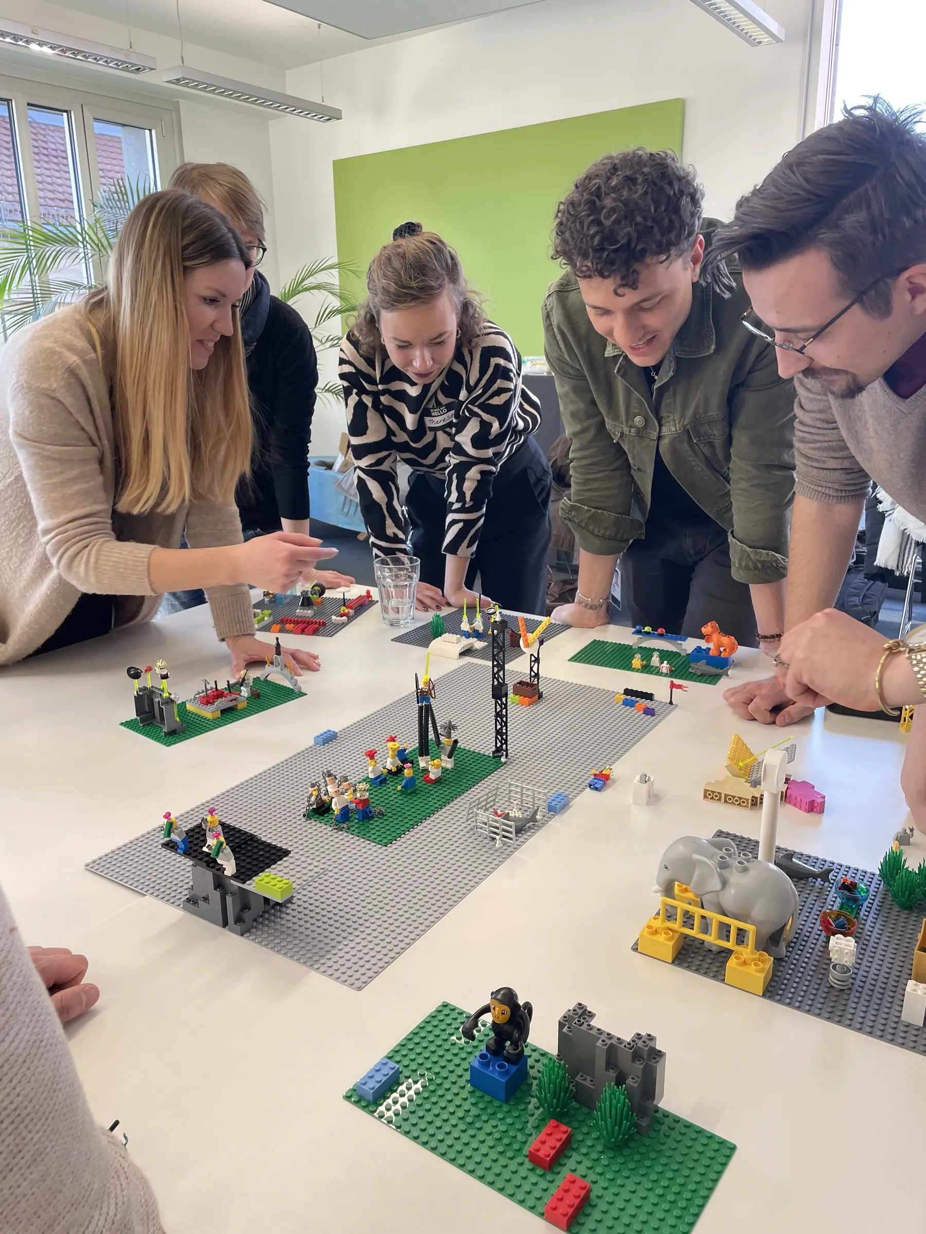 Team baut lachend an einer LEGO-Landschaft