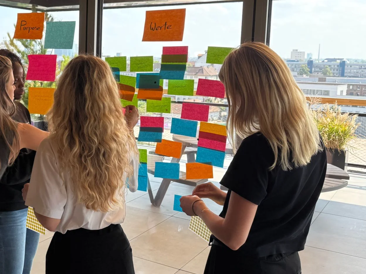 Team clustert Karten zu Purpose und Werten an einer Glasfront