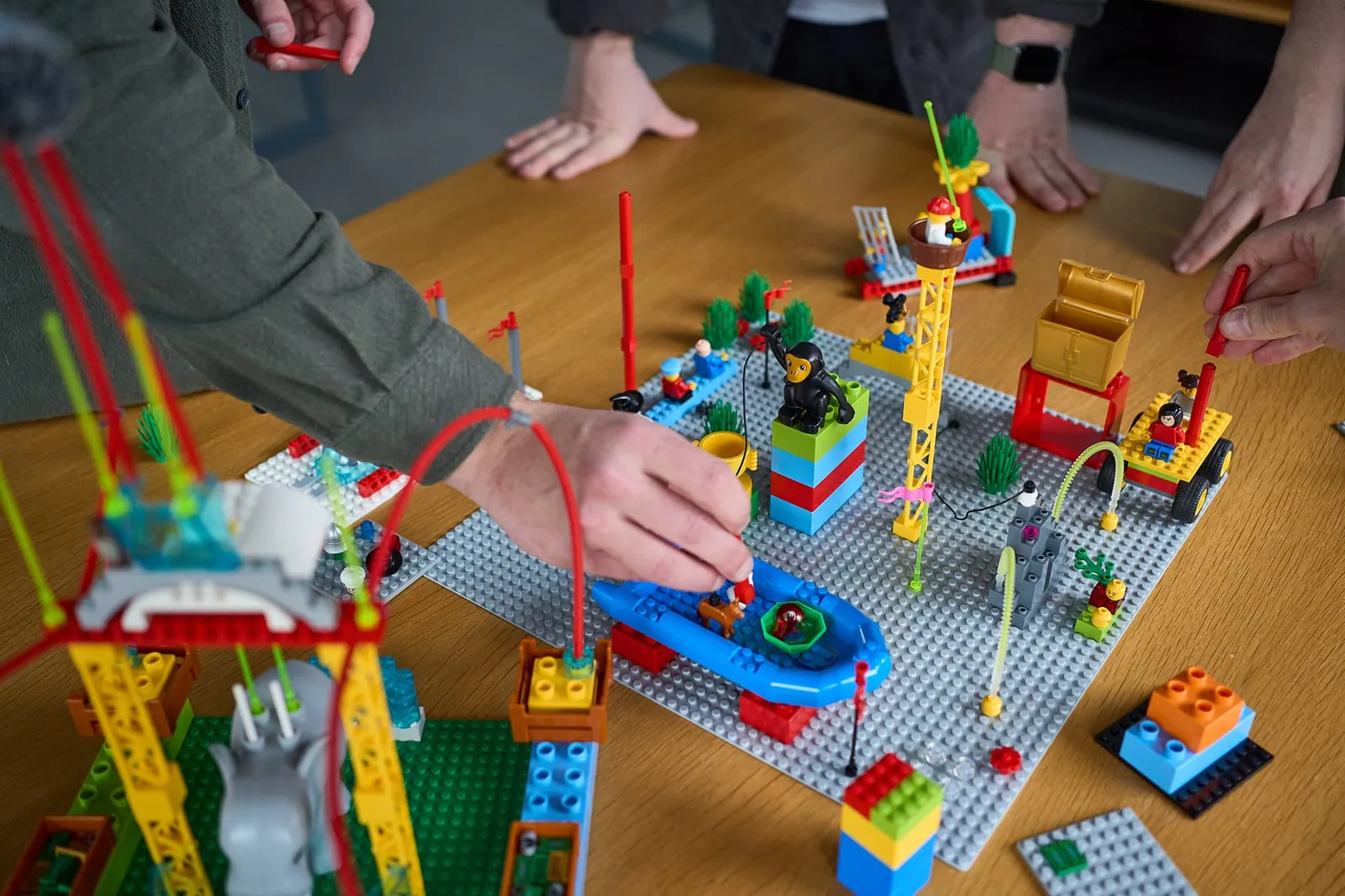 Teilnehmende in einem LEGO® SERIOUS PLAY® Workshop bauen Modelle mit bunten Steinen, um Strategien und Ideen sichtbar zu machen.